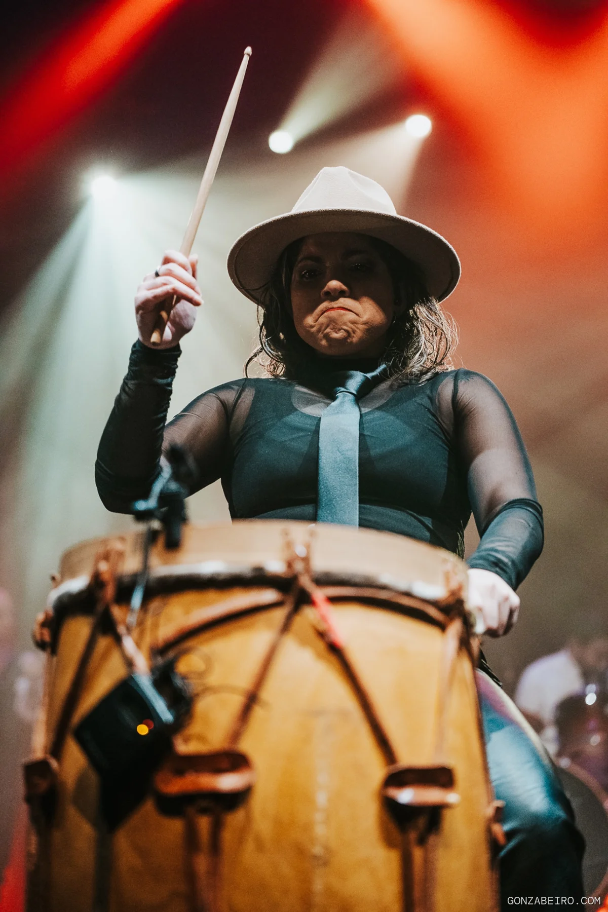 Una percusionista toca un tambor bajo luces cálidas.